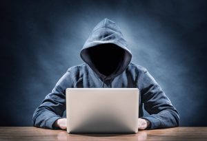 anonymous in a hoodie on a laptop