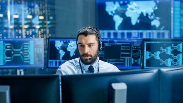 A man working in a security monitoring room