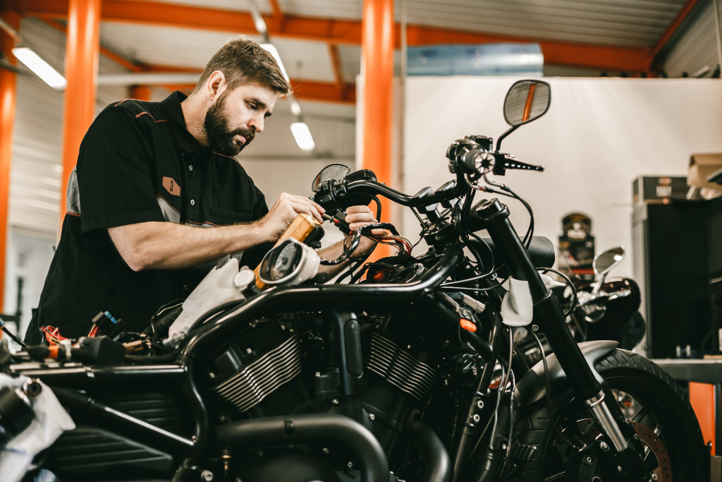 male repair worker repairing and maintaining a black sports motorcycle